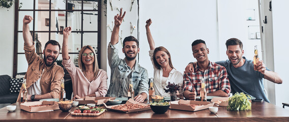 Fototapeta premium Group of happy young people having dinner with pizza indoors together