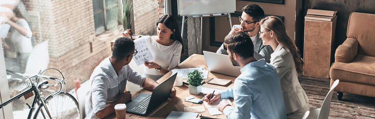 Group of young business people discussing strategy while having meeting in the office
