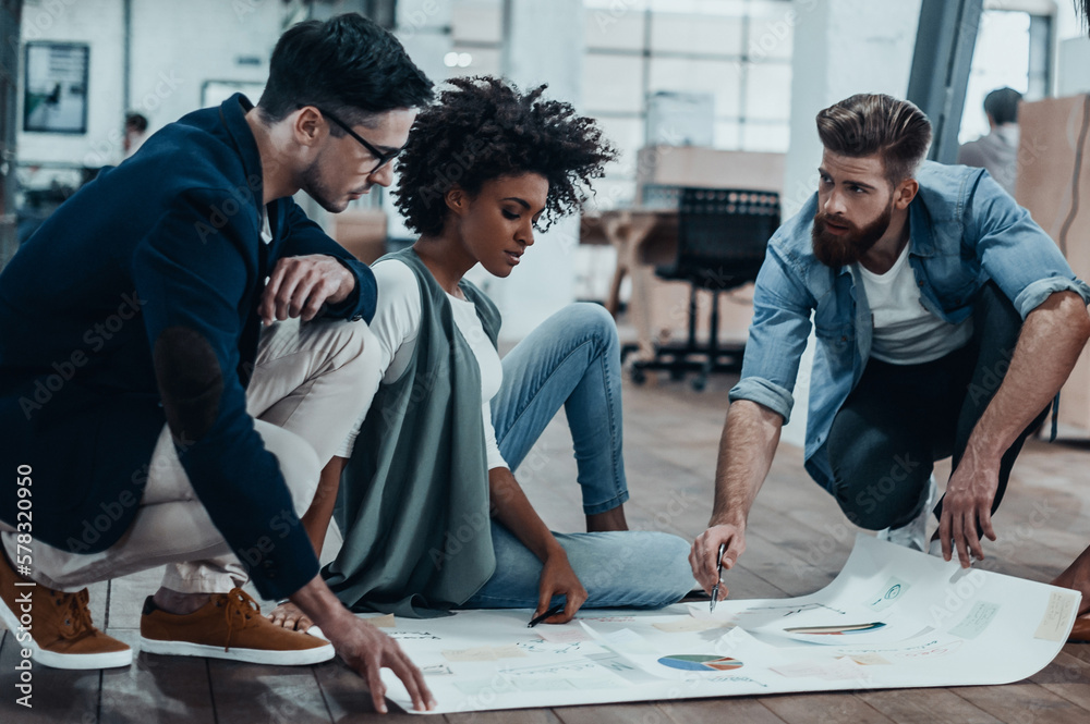 Canvas Prints group of confident business people discussing strategy while looking through a blueprint together