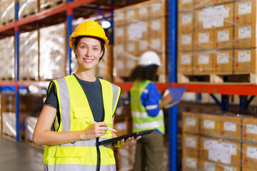 Happy cheerful caucasian white female warehouse worker checking or inspecting a stock inventory in...