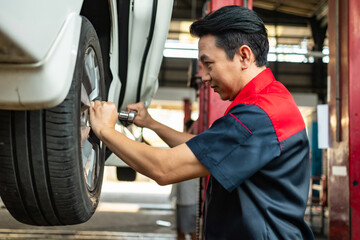 Asian  automotive senior engineer people work in mechanics garage.Auto mechanic in uniform is looking at camera and smiling examining car...