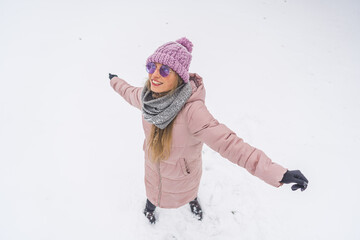 Fototapeta na wymiar cheerful long-haired woman standing in the snow and having fun, full shot winter concept. High quality photo