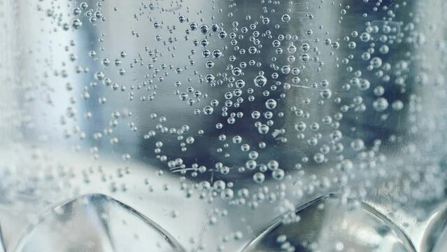 Glass water in side view with fresh sparkling water in a glass tumbler with bubbles and swirls. Clear glass beaker with water