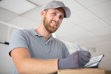 young courier delivery man in uniform holding a clipboard