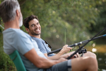 happy friends with fishing rods at lake or river