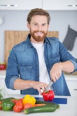 Fototapeta premium smiling young man chopping vegetables in the home