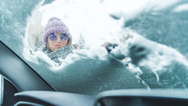 young woman moving snow from windshield, winter and snow concept. High quality photo