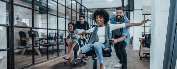 Group of happy business people having fun while racing on office chairs together