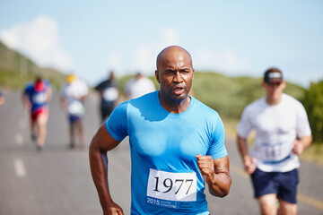 Fototapeta premium The race is on. a young man running ahead of the pack in a marathon.