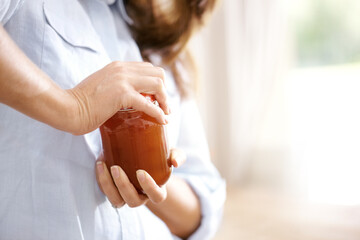 The lid is really tight. Cropped image of a woman trying to open a jar in the kitchen.