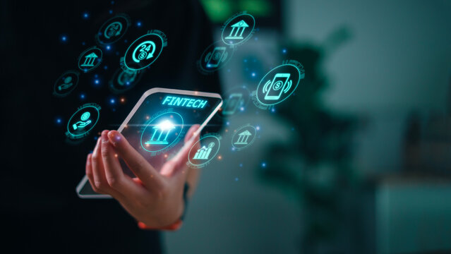 Fintech financial technology on smartphone concept. Hand with smartphone and text fintech and financial icons on the futuristic virtual interface screen.