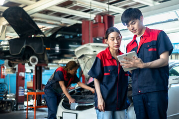 Fototapeta na wymiar Asian automotive engineer people wear helmet work in mechanics garage.young auto mechanic in uniform is looking at camera and smiling examining car.