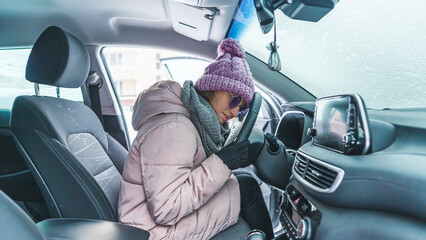 disappointed young woman in winter clothes sitting in the frozen car which does not work, winter concept. High quality photo