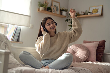 Fototapeta premium Caucasian teenage girl wearing headphones and listening music from her phone