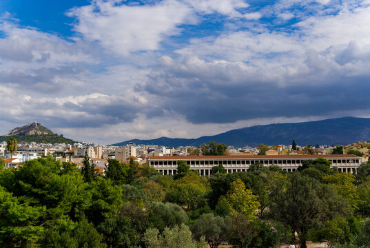 The Stoa of Attalos surrounded by hills covered in greenery under the cloudy sky in Greece