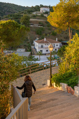 Fototapeta na wymiar Woman descends steps in the picturesque white village of Totalan, Malaga, Spain.