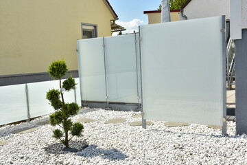 Terrasse und Gartenbereich mit Ziergehölz und Schotterbeet hinter einem Wohnhaus mit...