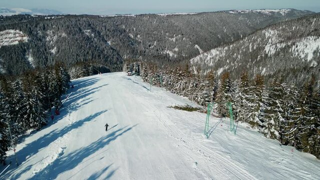 rone view of lonely skier on ski slope, with panoramic view of beautiful snowy mountains, in Romania, wide, tracking, 4K