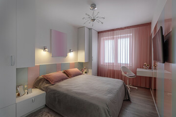 A modern bedroom in blue, pink and white colors with muffled lighting. Real photo