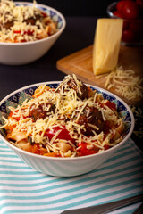 Classic italian tagliatelle spaghetti pasta with tomato sauce, meatballs, parmesan cheese and basil in plate on dark table. Dark food, dark mood