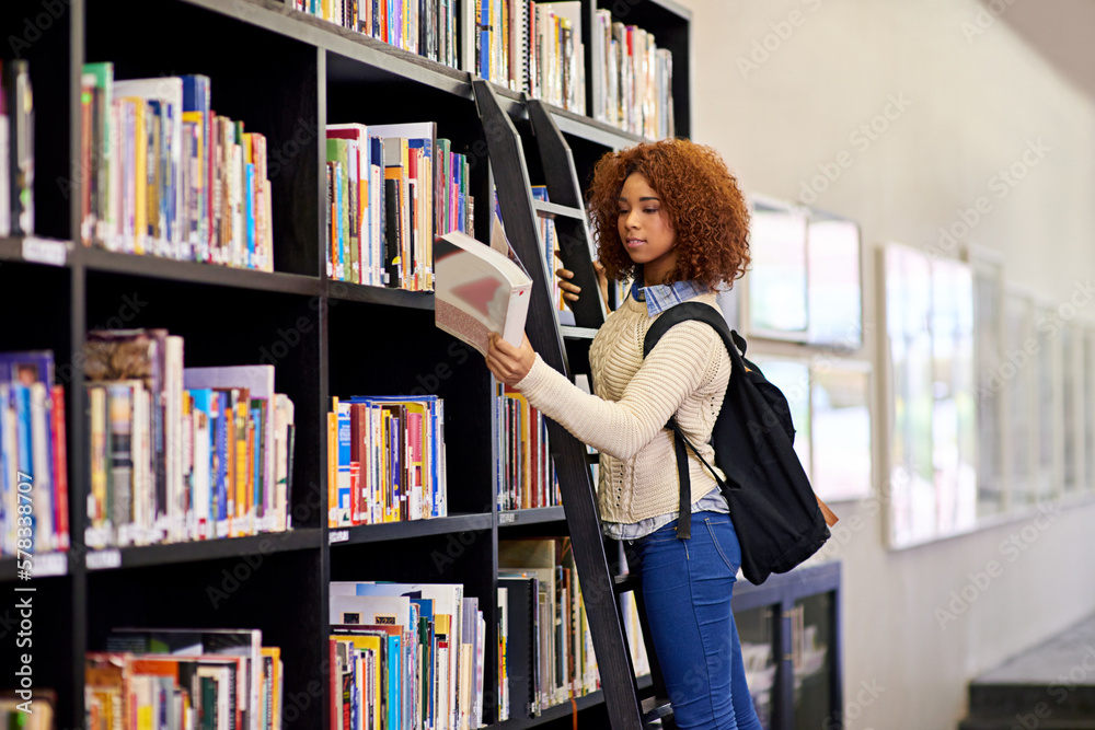 Poster she found what she was looking for. a young woman studying from a book while standing by a library b