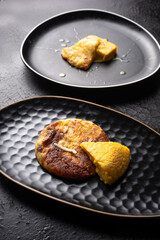 plates of frico and polenta on dark table. typical dish of Friuli