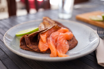 healthy breakfast of pieces of salted smoked salmon with buckwheat pancakes and lime