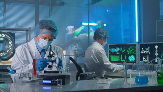 Modern medical research laboratory. The researcher examines the sample in a microscope. The second scientist types on the keyboard and enters research data into the computer.