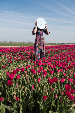 woman in classic dress in field of tulips holding mirror
