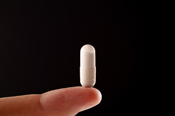 The pill on the finger extra close up. The white pill extra macro view.
