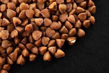 Buckwheat groats on a black background. Macro. Close-up