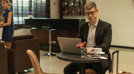 A male traveler enjoys using airline business lounge at a terminal waiting for departure. Business man uses computer laptop to check his travel plan and boarding in a lobby room.