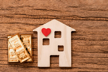 Obraz na płótnie Canvas House model with heart and the gold bar with growing value put on the old wood in the office, Saving for buy house or loan for business investment real estate concept.