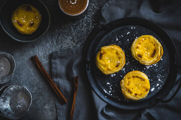 Traditional portuguese dessert, pastel de nata, pasteis de nata, egg tart, on dark gray background, top view