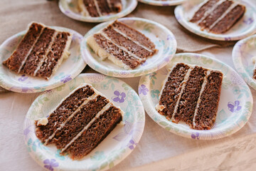 slices of carrot cake with cream cheese frosting on floral paper plates sitting out on table