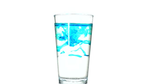 Drops of blue paint in a glass of water. glass of water