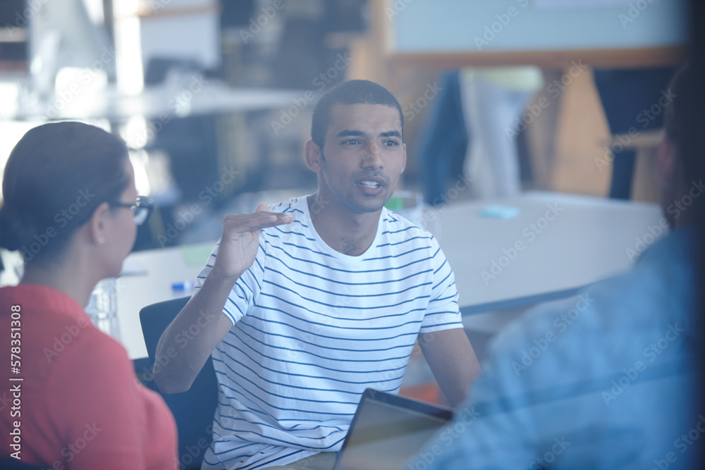 Poster sharing ideas with the team. through the glass shot of a group of designers discussing ideas in a me