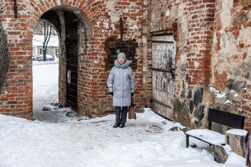 a woman in a gray coat travels to the sights in the vicinity of Veliky Novgorod in winter