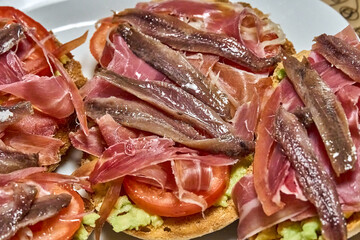 Suggestive Iberian ham toasts, tomato slices and fresh avocado.