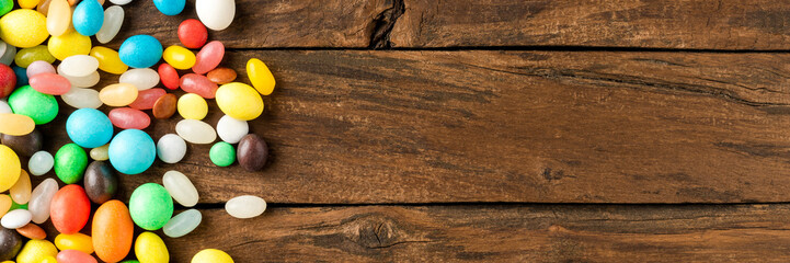 Mixed colourful candies on wooden background with copyspace