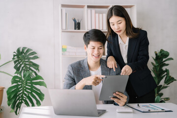 Photo of cute cheerful young couple using laptop and analyzing their finances with documents.