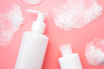 Obraz na płótnie Canvas Cosmetic template mockup. White plastic bottles with air foam on pink background. Face wash, mousse, soap, shampoo, shower gel. Beauty, spa, skin care, cosmetic product top view flat lay