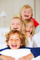 Joyful little brothers and sisters having fun in bed. Portrait of joyful little brothers and sisters on top of one another in bed.