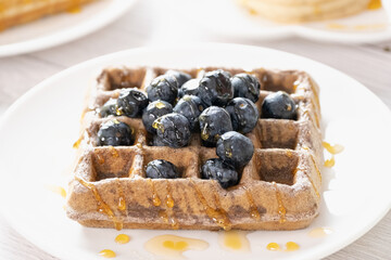 Belgian waffles with fruits berries and honey maple syrup set on white cafe table. - 578353159