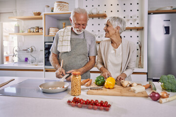 An elderly couple having fun in the kitchen preparing healthy food