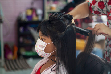 Asian little girl wearing a mask to prevent the Novel Coronavirus disease starting in 2019...