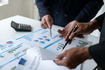 A group of Asian businessmen are brainstorming to analyze financial reporting situations. Find information from documents financial account for Calculating investments, income, taxes at office desk.