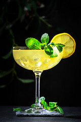 White lady alcoholic cocktail with dry gin, liquor, lemon juice and ice in wine glass. Black background