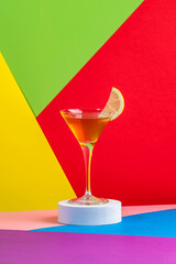 Yellow bird cocktail with white rum, liquor and lime juice in martini glass. Modern style still life on bright multicolored background