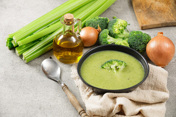 Creamy broccoli soup in a black plate on a gray background